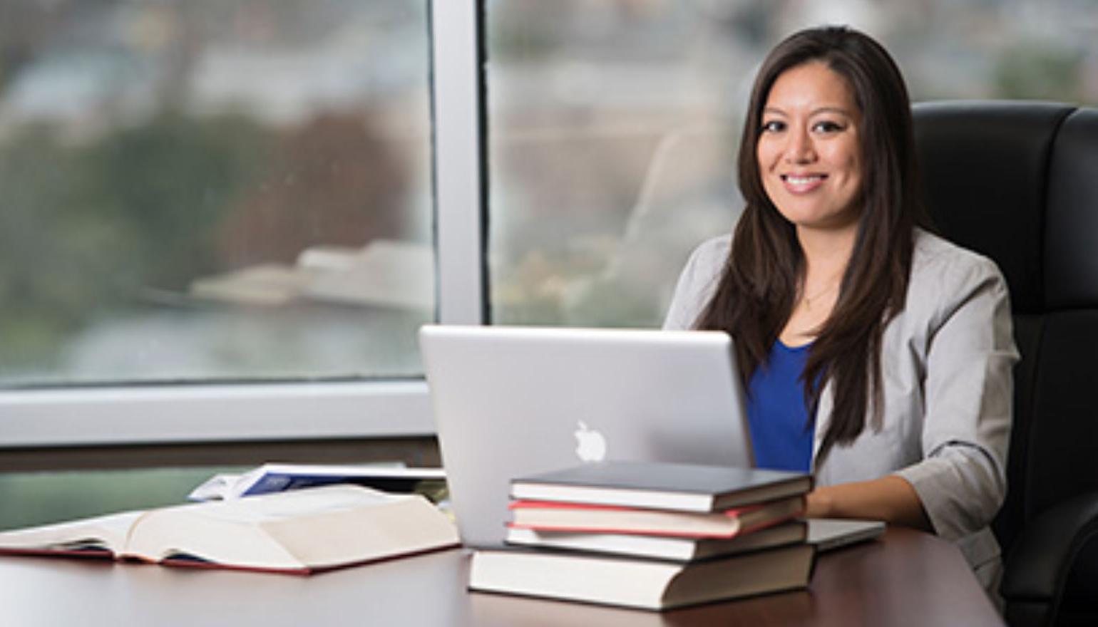 Graduate student studying with laptop and books